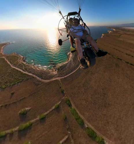 Tandem paramotor flight over the Sinis Coast at sunset